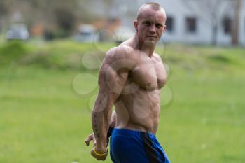 Bodybuilder Performing Side Triceps Poses In Park