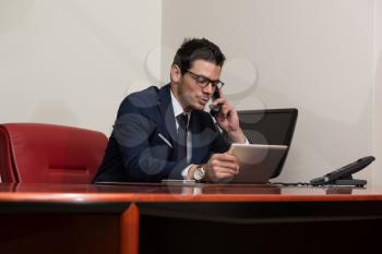 Young Businessman Working At His Computer While Talking On The Phone