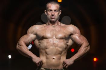 Bodybuilder Performing Front Lat Spread Poses In Tunnel