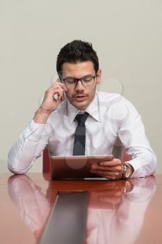 Young Businessman Working At His Tablet While Talking On The Phone