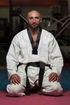 Black Belt Karate Man Sit On A Position To Start Or Finish Practicing