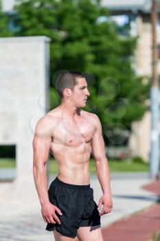 Serious Men Standing Outdoors And Flexing Muscles