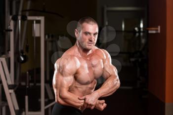 Serious Bodybuilder Standing In The Gym And Flexing Muscles