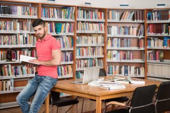 In The Library - Handsome Arabic Male Student With Laptop And Books Working In A High School - University Library - Shallow Depth Of Field