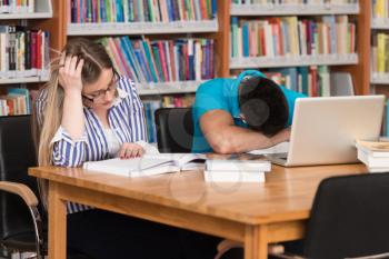 Stressed Students In High School Sitting At The Library Desk - Shallow Depth Of Field