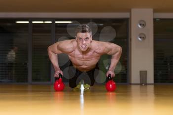 Young Adult Athlete Doing Push Ups On Kettle Bell As Part Of Bodybuilding Training