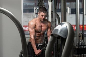 Young Bodybuilder Is Working On His Triceps With Cable In A Dark Gym