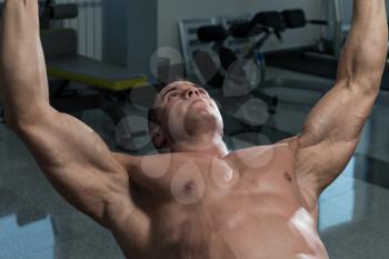 Young Man In Gym Exercising Chest With Dumbbells
