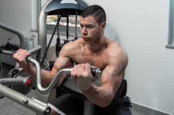 Young Athlete Doing Heavy Weight Exercise For Biceps On Machine