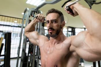 Young Man Bodybuilder Is Working On His Biceps With Cables In A Gym