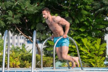 Young Man Exercising Triceps At Swimming Pool