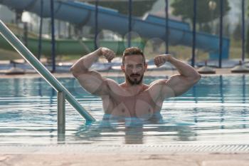 Portrait Of A Very Muscular Sexy Man In Underwear At Swimming Pool Showing Double Biceps Pose