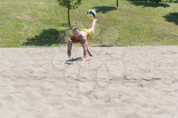 Muscular Young Man Playing Beach Volleyball Diving After The Ball