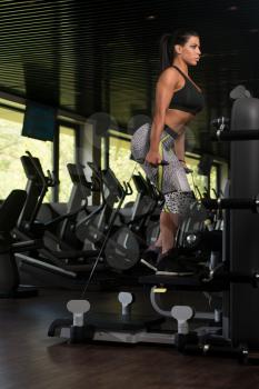 Young Latin Woman Working Out Legs On Machine In Fitness Center