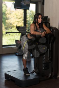 Young Latin Woman Working Out Legs On Machine In Fitness Center