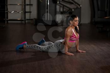 Young Woman Doing Stretching Exercises On The Floor At The Gym