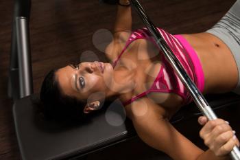 Young Latino Woman In Gym Exercising On The Bench Press