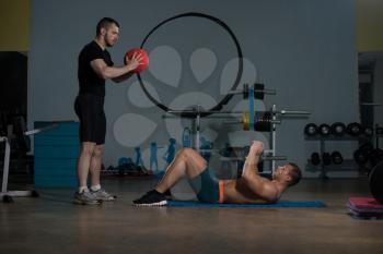 Young Man With Personal Trainer Doing Medicine Ball Exercises