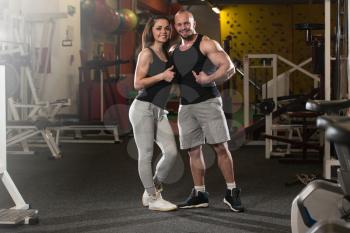Portrait Of A Sexy Couple In The Gym With Exercise Equipment Showing Thumbs Up