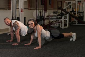 Couple Doing Pushups As Part Of Bodybuilding Training In The Gym
