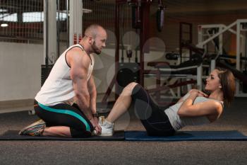 Young Couple Doing Sit Ups As Part Of Bodybuilding Training In The Gym