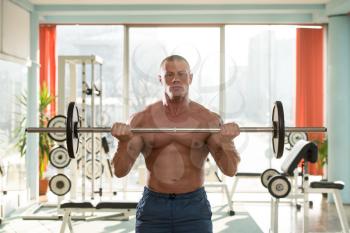 Muscular Man Doing Heavy Weight Exercise For Biceps With Barbell