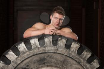 Young Muscular Man with Truck Tire Resting Afther Doing Style Workout Turning Tire Over