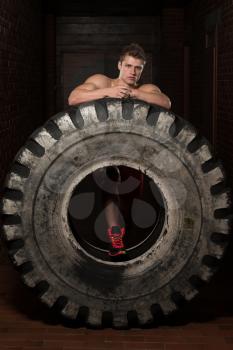 Young Muscular Man with Truck Tire Resting Afther Doing Style Workout Turning Tire Over