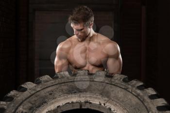 Young Muscular Man With Truck Tire Doing Style Workout Turning Tire Over