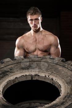Young Muscular Man With Truck Tire Doing  Style Workout Turning Tire Over