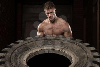 Young Muscular Man With Truck Tire Doing Style Workout Turning Tire Over