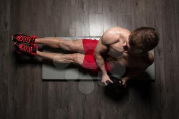 Healthy Young Man Exercising Abdominals On Foor With Weights
