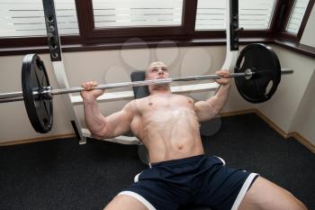 Muscular Man Doing Heavy Weight Exercise For Chest On Bench Press In Gym