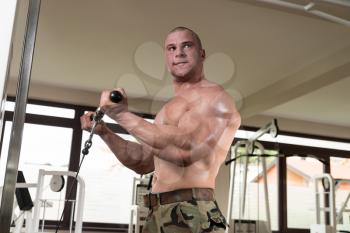 Muscular Man Doing Heavy Weight Exercise For Biceps On Machine In Gym