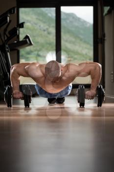 Young Man Push-Up Strength Pushup Exercise With Dumbbell In A Gym Workout