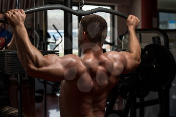 Bodybuilder Doing Heavy Weight Exercise For Back On Machine In Gym