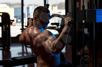 Bodybuilder Doing Heavy Weight Exercise For Back On Machine In Gym