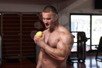 Male Sportsman Bites Green Apple After Training