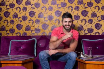 Young Man Drinking Coffee In The Cafe Bar With Colorful Walls On Background