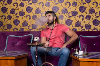 Man Smoking Turkish Hookah In The Cafe With Colorful Walls On Background