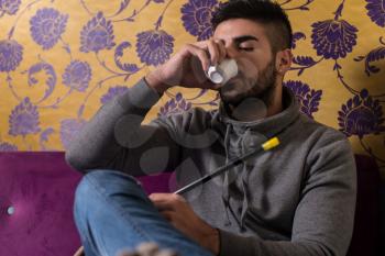 Young Man Smoking Shisha At Arabic Restaurant - Man Exhaling Smoke Inhaling From A Hookah