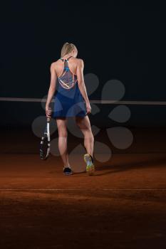 Portrait Of Female Tennis Player With Racket Ready To Hit A Tennis Ball - Back View