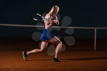 Young Female Tennis Player With Racket Ready To Hit A Tennis Ball