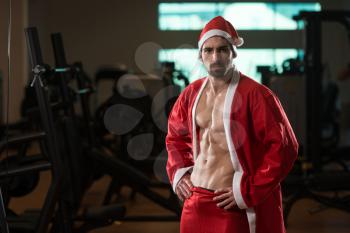Young Muscled Man In Santa Claus Outfit Posing In A Fitness Center Gym