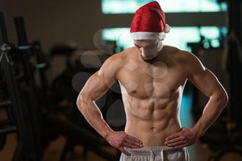 Portrait Of A Young Santa Claus Posing And Showing Bodybuilding Pose In Gym