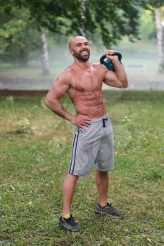 Muscular Adult Caucasian Man Doing A Exercise Outdoors With Kettlebell