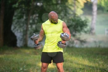 Muscular Adult Caucasian Man Doing A Exercise For Biceps With Dumbbells Outdoors Workout