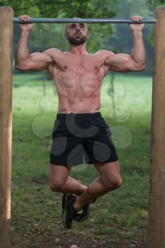 Muscular Built Young Athlete Working Out In An Outdoor Gym - Doing Chin-Ups