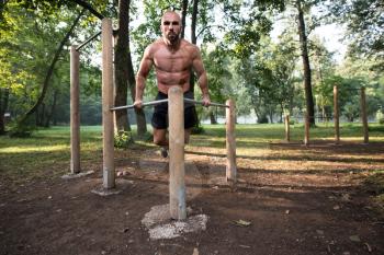 Young Athlete Working Out Triceps In An Outdoor Gym - Doing Street Workout Exercises
