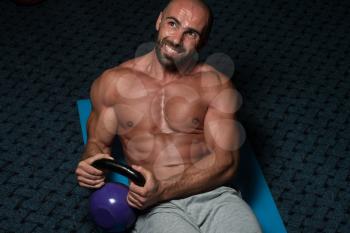 Muscular Man Exercising Abs Abdominals With Kettlebell On Floor